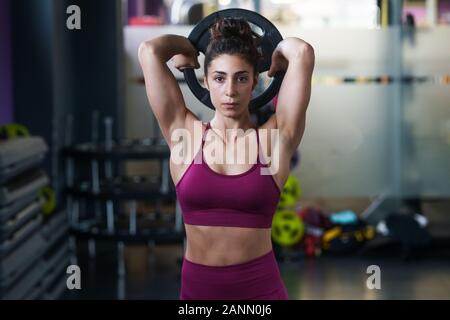 Athletische Frau tun Trizeps Push-ups mit einem barbell Platte Stockfoto