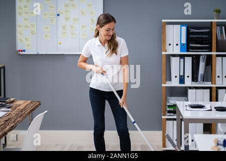 Weibliche Hausmeister wischen Stock in modernen Büro Stockfoto