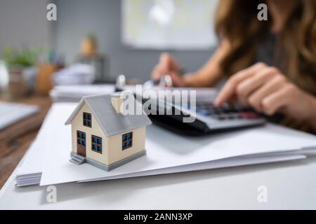 Nahaufnahme einer Person Hand Berechnung Immobilien Steuer auf hölzernen Schreibtisch Stockfoto