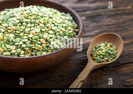 Trocken grüne Erbsen in einer Platte auf einem braunen Holz- Hintergrund. Bohnen für nahrhafte Suppe Stockfoto