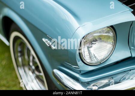 Nahaufnahme eines klassischen blauen ford Mustang-Scheinwerfers aus dem Jahr 1966 und eines Details an der Vorderseite, die das legendäre Design und die Chromelemente zeigen Stockfoto