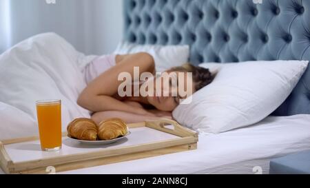 Mädchen schlafen im Bett, gesundes Frühstück in der Nähe von Bed, guter Service, geliebte Überraschung Stockfoto