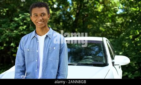 Junge schwarze Mann lächelnd auf Cam, lehnte sich neuen Automobil, Führerschein Stockfoto