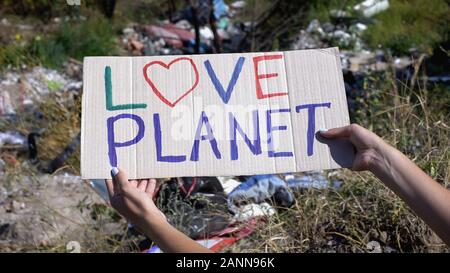 Liebe Planet Phrase auf Pappe in Person die Hände gegen Deponie Hintergrund Stockfoto