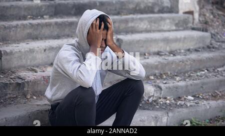 Junge schwarze Mann draußen sitzen, emotionaler Mißbrauch niedergedrückt, Problem Stockfoto