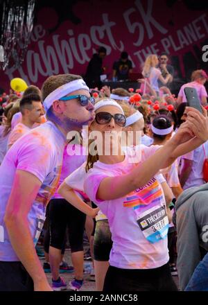 Mann und Frau feiern den Abschluss Des Color Run in Birmingham 2015, indem sie ein selfie auf das Handy nehmen und dabei albern Gesichtsausdrücke ziehen Stockfoto