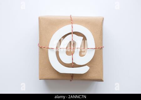 Flach von verpackten Paket mit e-Mail Symbol auf weißem Hintergrund minimal kreative Postzustellung Konzept isoliert. Stockfoto