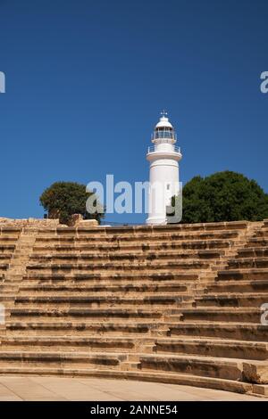 Die Ansicht der Sitze Reihen von Odeon mit Leuchtturm auf dem Hintergrund im archäologischen Park Paphos. Zypern Stockfoto