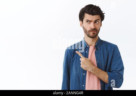 Skeptisch und besorgt unentschlossen bärtiger Mann im Hemd über t-shirt, auf der linken oberen Ecke, stirnrunzelnd und beißen Lippe nervös und dachte, wenn er Ri gemacht Stockfoto