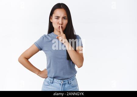 Stille in der Klasse. Ernst - auf der Suche wütend Bossy asiatischen Mädchen deman ruhig, sagen Shh, drücken Sie den Zeigefinger auf die Lippen als Sie shushing Für laut und runzelte die Stirn Stockfoto