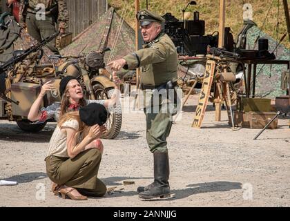 UK, Rothley - Juni 2018: Kriegszeiten deutscher Offizier in der Armee droht weibliche französische Widerstandskämpfer Stockfoto