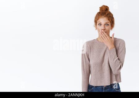 Überrascht und neugierig gut aussehende weibliche rothaarige Frau mit lockigem Haar, Verschleiß Pullover, lächelnd erstaunt, nach Luft schnappend, decken Sie Mund und starre Kamera fas Stockfoto