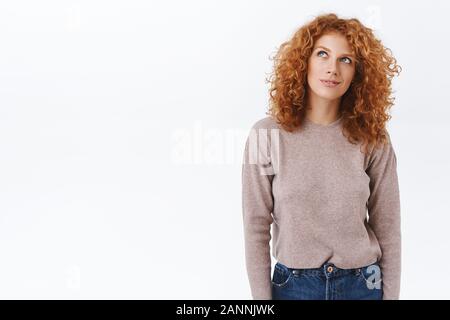 Verträumt, kreative gut aussehende redhead Curly girl in Bluse, Jeans, schaut nachdenklich lächelnd verschlagen, picturing etwas Schönes oder leckere, Hav Stockfoto