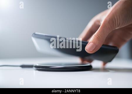Frau Laden Smartphone mithilfe des Wireless Charging Pad zu Hause Stockfoto