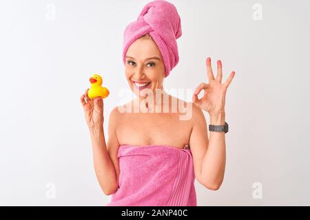 Mittleres Alter Frau mit Handtuch holding Ente Spielzeug über isoliert weißer Hintergrund tun ok Zeichen mit den Fingern Dusche, ausgezeichnete Symbol Stockfoto