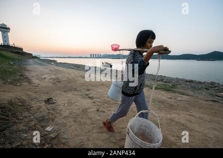 Eine Frau mit zwei großen Eimer Wasser auf ihre Schulter, abgerufen aus dem Xi Fluss, Zhaoqing, Guangdong, in China Stockfoto