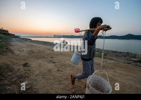 Eine Frau mit zwei großen Eimer Wasser auf ihre Schulter, abgerufen aus dem Xi Fluss, Zhaoqing, Guangdong, in China Stockfoto