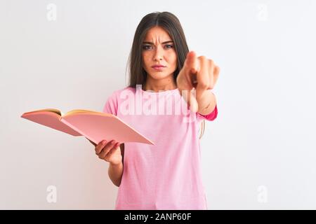 Junge hübsche Studentin Frau liest Buch über isoliert weißer Hintergrund mit dem Finger an die Kamera und an Sie gerichtet, Handzeichen, positiv Stockfoto