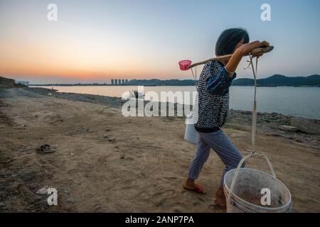 Eine Frau mit zwei großen Eimer Wasser auf ihre Schulter, abgerufen aus dem Xi Fluss, Zhaoqing, Guangdong, in China Stockfoto