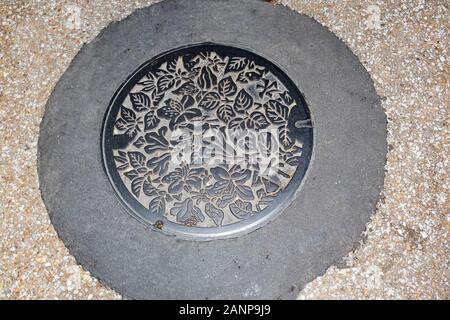 Takayama, Japan - November 5., 2018: ein Metall Abwasserkanal Deckel, mit Blüten und Blättern verziert, auf einer Straße in Takayama, Japan Stockfoto