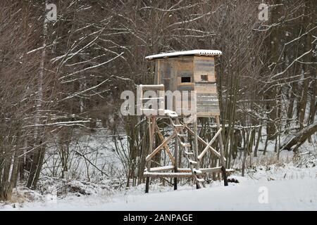 Holz- Jagd im Winter am Rande des Waldes sitzen Stockfoto