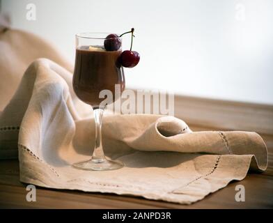 Mousse Schokolade, Vanille Mousse, Schokoladensauce in ein Glas mit zwei Kirschen auf dem Holztisch. Im rustikalen Stil. Mousse au Chocolat mit Schlagsahne Stockfoto