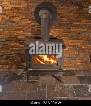 Das Verbrennen von Holz Herd mit Stein Wand Hintergrund Stockfoto
