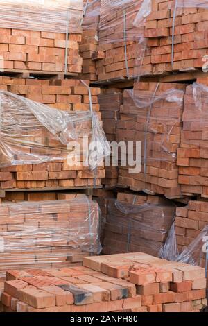 Mehrere Paletten mit Beton Ziegel übereinander im Depot gestapelt. Die industrielle Produktion von Backsteinen. vertikale Foto. Stockfoto