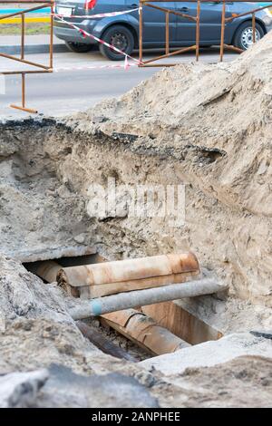 Rostige Kanalisationsrohre - Unterirdisch. Reparatur der Erdwasserversorgung, vertikales Foto. Stockfoto