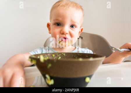 Kleiner Junge allein isst Püree aus einer Platte. Stockfoto