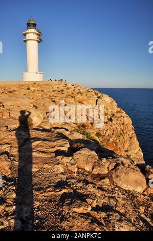 Der lange Schatten des Fotografen und Cap de Barbaria Leuchtturm bei Sonnenuntergang (Formentera, Pityusic Inseln, Balearen, Mittelmeer, Spanien) Stockfoto