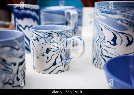 Weißen Fayencen Becher mit blauen Flecken auf einem Tisch zum Verkauf. Handgefertigt. Stockfoto