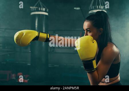 Aktion geschossen von Junge athletische Frau Training mit Boxsack Boxhandschuhe tragen gelbe Stockfoto
