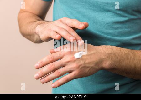 Nahaufnahme Blick auf männliche Hände feuchtigkeitsspendend seine Hände mit Sahne Stockfoto