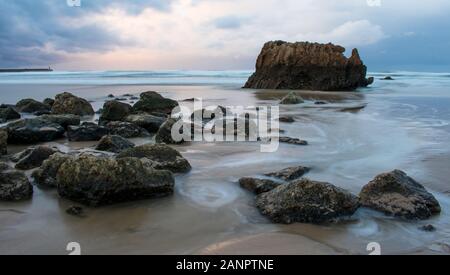 Wellen Felsen und Sonnenuntergang am Strand Stockfoto