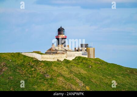 Schwarzer Leuchtturm in Ballycotton, Cork, Irland mit blauem Himmel und grünem Land. Das Wahrzeichen des Leuchtturms ist ein Warnschild für Schiffe und Boote der Küstenlinie Stockfoto