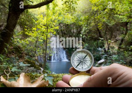 Des Menschen Hand mit einem Kompass im Wald, Konzept der Suchenden, Exploration, Leistung. Selektiver Fokus Stockfoto