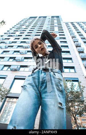 Urban Style. Junge stilvolle Frau, die in der Nähe von Skyscraper posing Unterseite Hände gekreuzt hinter Kühlen Stockfoto