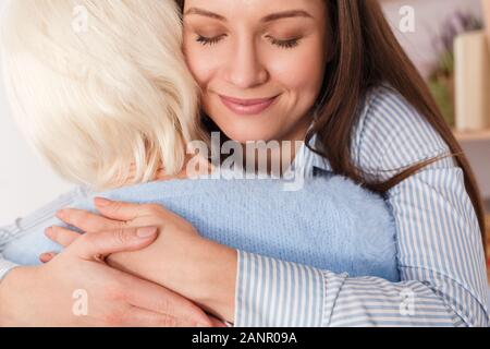 Erwachsene Tochter umarmt ihre reife Mutter zu Hause Stockfoto