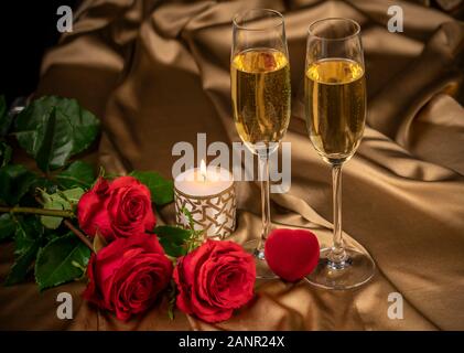 Valentinstag Karte, zwei Gläser Champagner auf einen goldenen Hintergrund, rote Rosen und ein rotes Herz, eine brennende Kerze. Stockfoto