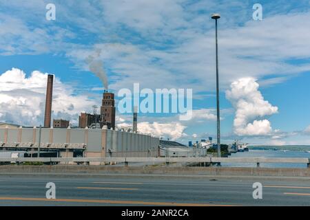 Konzept der Umweltverschmutzung. Der Rauch aus den Schornsteinen, vermischt sich mit den Wolken im blauen Himmel. Kanada. Stockfoto