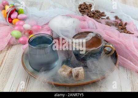 Traditionellen türkischen Kaffee in Porzellan Schale setzen, ein Glas Wasser und türkischem Honig, bunte Mandel Bonbons auf der Oberfläche mit Kaffeebohnen. Ein Fest (f Stockfoto