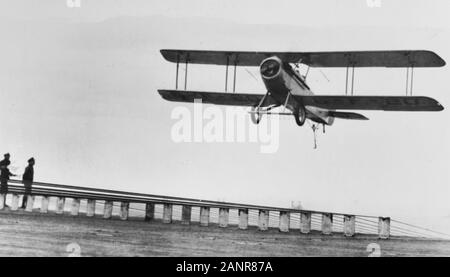 VOUGHT VE-7s VE-7s der Kämpfe Squadron 6 (VF-6), Landung an Bord der USS LANGLEY (CV-1) ca. 1927. Unter Flügel Kennzeichnung "6-F-16' zeigt diese Ebene wird als ein Dienstprogramm Flugzeug über seine Kämpfer Kraft zu VF-6 angebracht. Träger Decks hatten die übliche Seitliche verhaften Drähte, sondern auch die Anordnung der vorderen und hinteren Drähten wie hier gesehen. Diese Drähte propped Up auf hölzernen "fiddle Blocks', das kleine Ankerförmigen gefangen werden die Haken an der Unterseite des Hauptfahrwerks Achse das Flugzeug von Schlenker von der Flight Deck zu beiden Seiten, wenn sein Schwanz haken die Verhaftung gefangen zu halten. Stockfoto