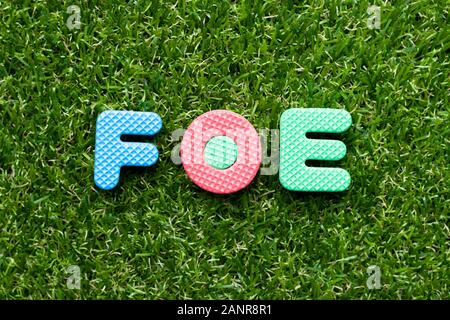 Spielzeug Schaumstoff Buchstaben im Wort Feind auf grünem Gras Hintergrund Stockfoto