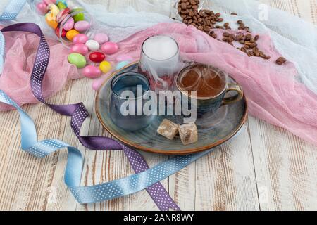 Traditionellen türkischen Kaffee in Porzellan Schale setzen, ein Glas Wasser und türkischem Honig, bunte Mandel Bonbons auf der Oberfläche mit Kaffeebohnen. Ein Fest (f Stockfoto