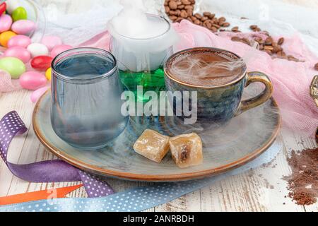 Traditionellen türkischen Kaffee in Porzellan Schale setzen, ein Glas Wasser und türkischem Honig, bunte Mandel Bonbons auf der Oberfläche mit Kaffeebohnen. Ein Fest (f Stockfoto