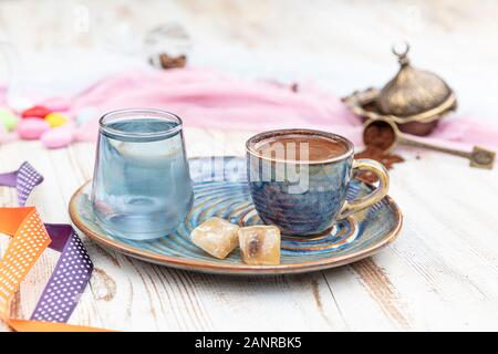 Traditionellen türkischen Kaffee in Porzellan Schale setzen, ein Glas Wasser und türkischem Honig, bunte Mandel Bonbons auf der Oberfläche mit Kaffeebohnen. Ein Fest (f Stockfoto