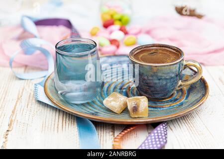 Traditionellen türkischen Kaffee in Porzellan Schale setzen, ein Glas Wasser und türkischem Honig, bunte Mandel Bonbons auf der Oberfläche mit Kaffeebohnen. Ein Fest (f Stockfoto