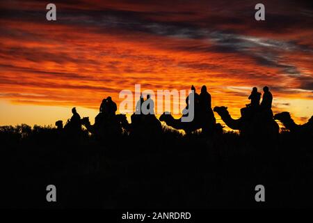Eine dramatische Silhouette bei Sonnenuntergang, die von einer Gruppe von Touristen auf einer Fahrt im Outback Australien verursacht wird. Yulara, Northern Territory, Australien Stockfoto