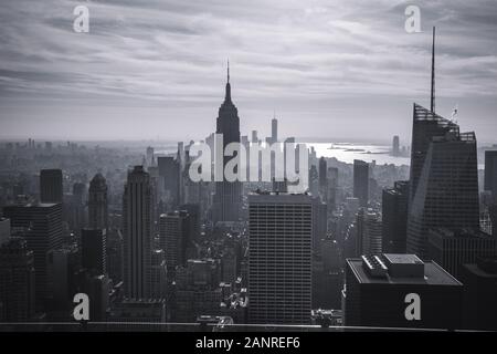 Blick auf Manhattan New York City aus einer Höhe. 2-in-1-Silhouetten der Wolkenkratzer, der Fluss schimmert in den Strahlen der untergehenden Sonne. Getonten Bild eines Stockfoto